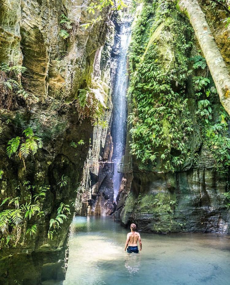 A man admires a waterfall from the pool below