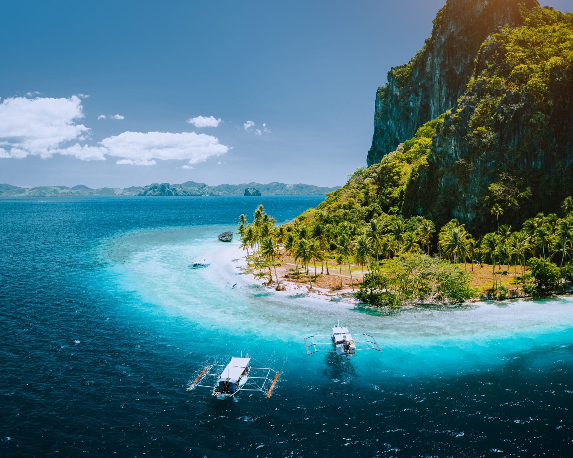 Epic aerial drone panoramic picture of tourist boats arriving tropical Pinagbuyutan Island with idyllic ipil beach surrounded by turquoise blue ocean water. El Nido, Palawan, Philippines