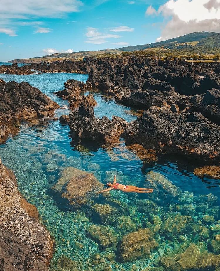 Woman floating in a crystal clear rock pool at Biscoitos