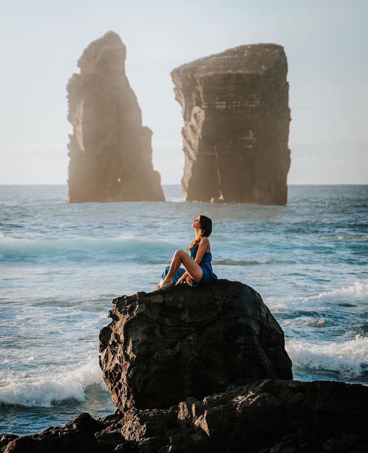 A woman posing in the sun on an ocean boulder at Praia dos Mosteiros - The 15 Best Beaches in Azores, Portugal