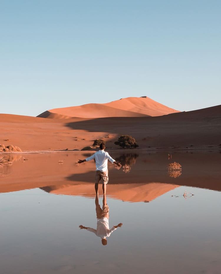 A man stands in a shallow pool in the dunes at Sossusvlei - The Best Places to See Wildlife in Namibia