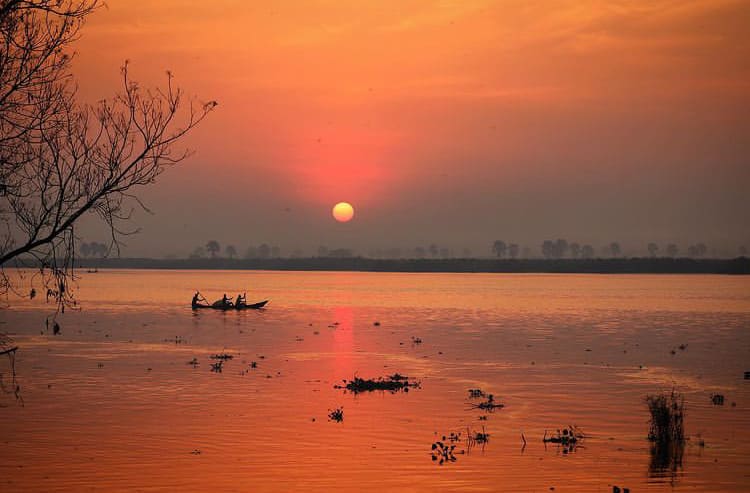 Fishermen rowing across Lake Albert as the sun sets