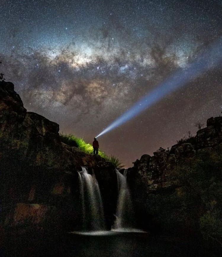 Stargazer using a torch to scan the starry African sky