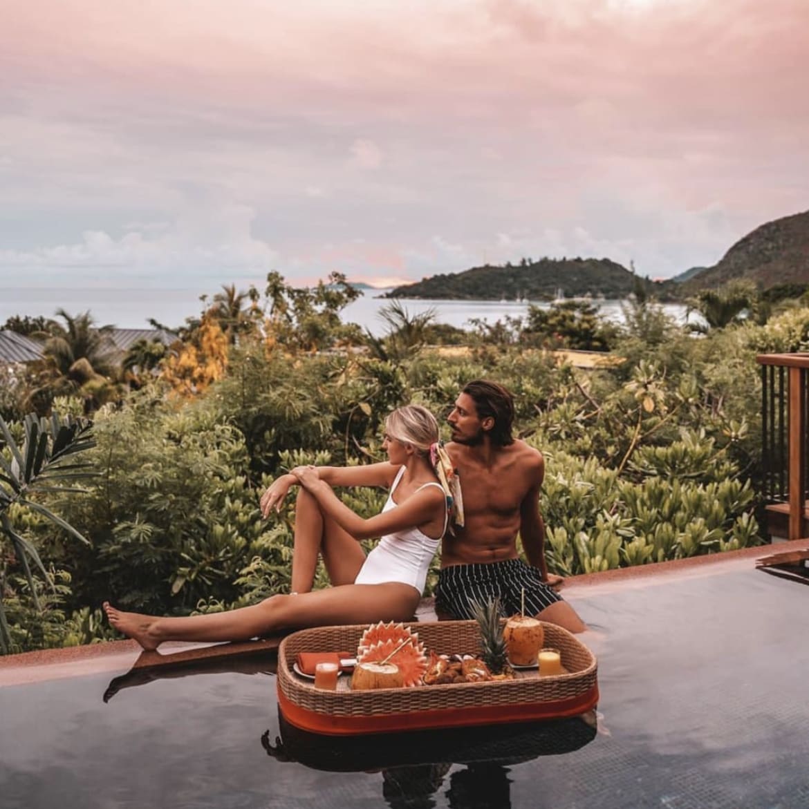 A couple enjoying the view from their swimming pool, while having a floating breakfast