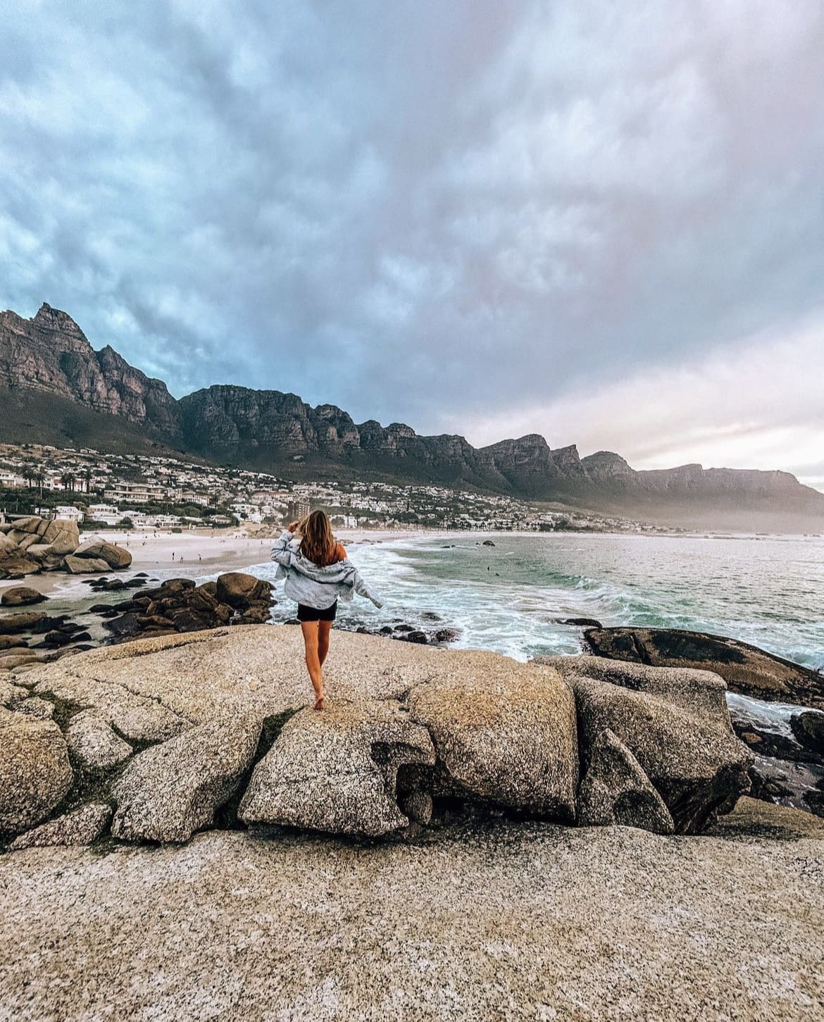 A woman admiring the view of table mountain from the beach in camps bay